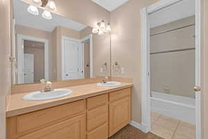 Bathroom featuring tile flooring, shower / washtub combination, large vanity, and dual sinks