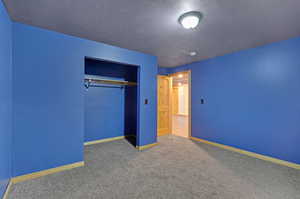 Unfurnished bedroom featuring a closet, carpet floors, and a textured ceiling