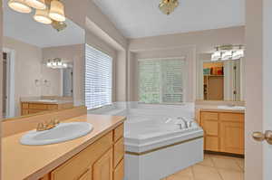 Bathroom with tile floors, tiled bath, and double sink vanity