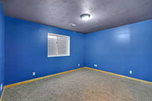 Carpeted empty room featuring a textured ceiling