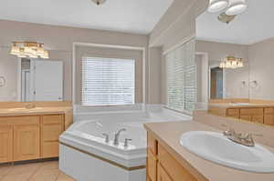 Bathroom with dual bowl vanity, tiled bath, and tile flooring