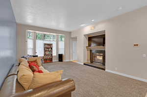 Carpeted living room with a premium fireplace and a textured ceiling