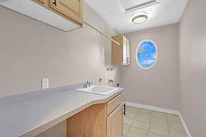 Laundry room with cabinets, hookup for an electric dryer, hookup for a washing machine, sink, and light tile flooring