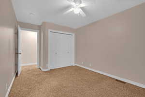 Unfurnished bedroom with a closet, carpet, and ceiling fan