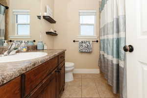 Bathroom featuring a healthy amount of sunlight, tile flooring, vanity, and toilet