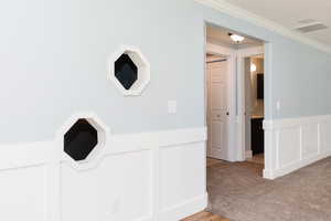 Corridor featuring light carpet and crown molding