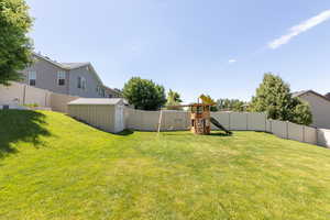 View of yard featuring a playground and a storage unit