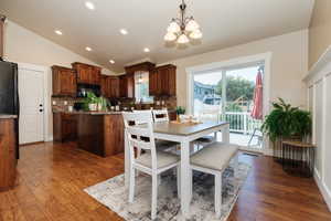 Dining area with a notable chandelier, vaulted ceiling, and dark hardwood / wood-style flooring