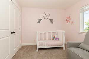 Bedroom with a nursery area and carpet floors