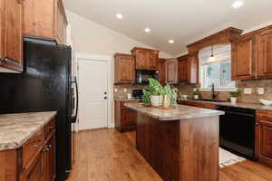 Kitchen with a center island, black appliances, sink, and backsplash