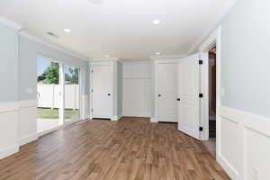 Unfurnished bedroom featuring multiple windows, hardwood / wood-style floors, access to outside, and ornamental molding