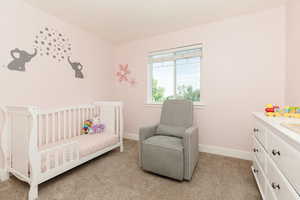 Carpeted bedroom featuring a crib