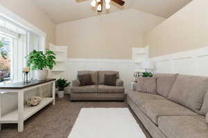 Carpeted living room featuring a healthy amount of sunlight, vaulted ceiling, and ceiling fan