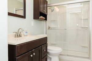 Bathroom with a shower with door, toilet, and oversized vanity