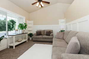 Living room featuring ceiling fan, dark colored carpet, and lofted ceiling