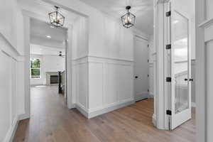 Hall with light wood-type flooring and an inviting chandelier