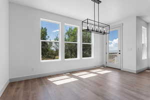 Unfurnished dining area with light hardwood / wood-style floors and an inviting chandelier