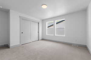 Unfurnished bedroom with a closet and light colored carpet