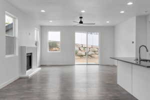 Unfurnished living room featuring dark hardwood / wood-style flooring, plenty of natural light, sink, and ceiling fan