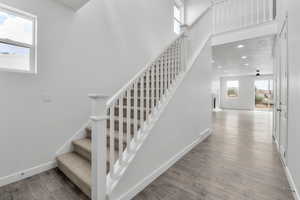 Stairway with hardwood / wood-style floors and a towering ceiling