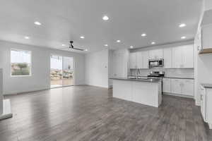 Kitchen with appliances with stainless steel finishes, dark hardwood / wood-style floors, white cabinetry, and ceiling fan