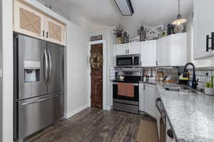 Kitchen featuring sink, dark hardwood / wood-style flooring, backsplash, and appliances with stainless steel finishes