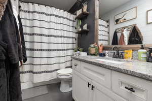 Bathroom featuring vanity with extensive cabinet space and toilet