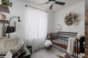 Bedroom with carpet floors, a crib, and ceiling fan