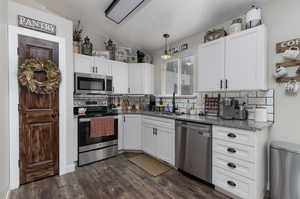 Kitchen featuring dark hardwood / wood-style floors, lofted ceiling, and appliances with stainless steel finishes