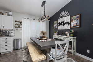 Dining area with dark wood-type flooring and lofted ceiling