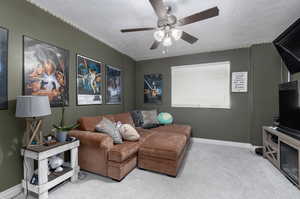 Living room with a textured ceiling, carpet floors, and ceiling fan