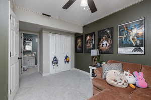 Interior space with ceiling fan, carpet floors, and a textured ceiling