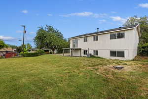 Back of property with central AC, a lawn, and a patio area