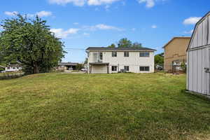 Back of house featuring a storage shed, a yard, and central AC unit