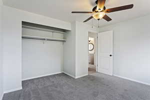 Unfurnished bedroom with a closet, ceiling fan, and dark carpet