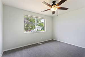 Carpeted spare room featuring ceiling fan