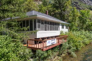 Back of property with a sunroom and a deck with water view