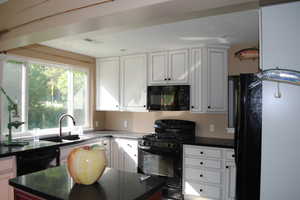 Kitchen with white cabinets, sink, and black appliances