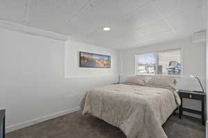 Carpeted bedroom with a drop ceiling and an AC wall unit