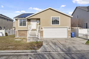 View of front of home featuring a garage and solar panels