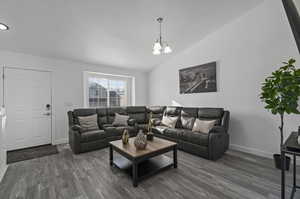 Living room featuring high vaulted ceiling, a notable chandelier, and dark wood-type flooring