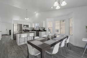 Dining area featuring high vaulted ceiling, dark hardwood / wood-style floors, sink, and a notable chandelier