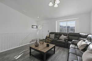 Living room featuring dark hardwood / wood-style flooring, a notable chandelier, and lofted ceiling