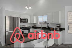 Kitchen featuring appliances with stainless steel finishes, sink, white cabinetry, and dark hardwood / wood-style floors