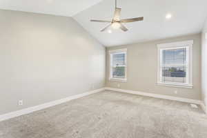 Carpeted empty room featuring ceiling fan and vaulted ceiling