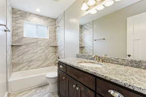 Full bathroom with toilet, tile flooring, tiled shower / bath combo, and oversized vanity