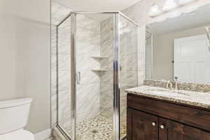 Bathroom featuring a shower with shower door, vanity, and toilet