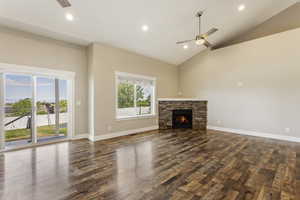 Unfurnished living room with high vaulted ceiling, dark hardwood / wood-style flooring, ceiling fan, and a fireplace