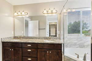 Bathroom featuring dual vanity and a relaxing tiled bath