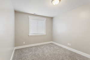 Spare room featuring a textured ceiling and carpet flooring